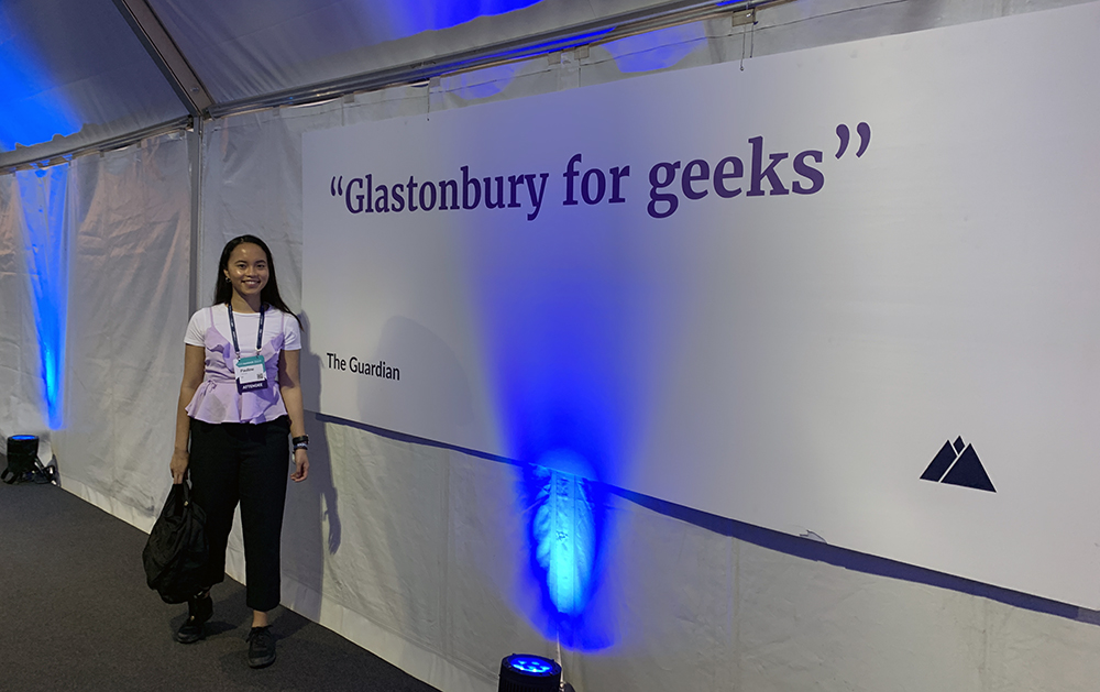 Pauline next to a sign that says "Glastonbury for geeks" to describe the conference